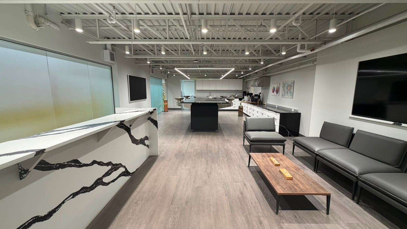 Une vue large de la salle de dégustation, un comptoir de marbre à gauche, un coin salon à droite et la table de dégustation noire au second plan.